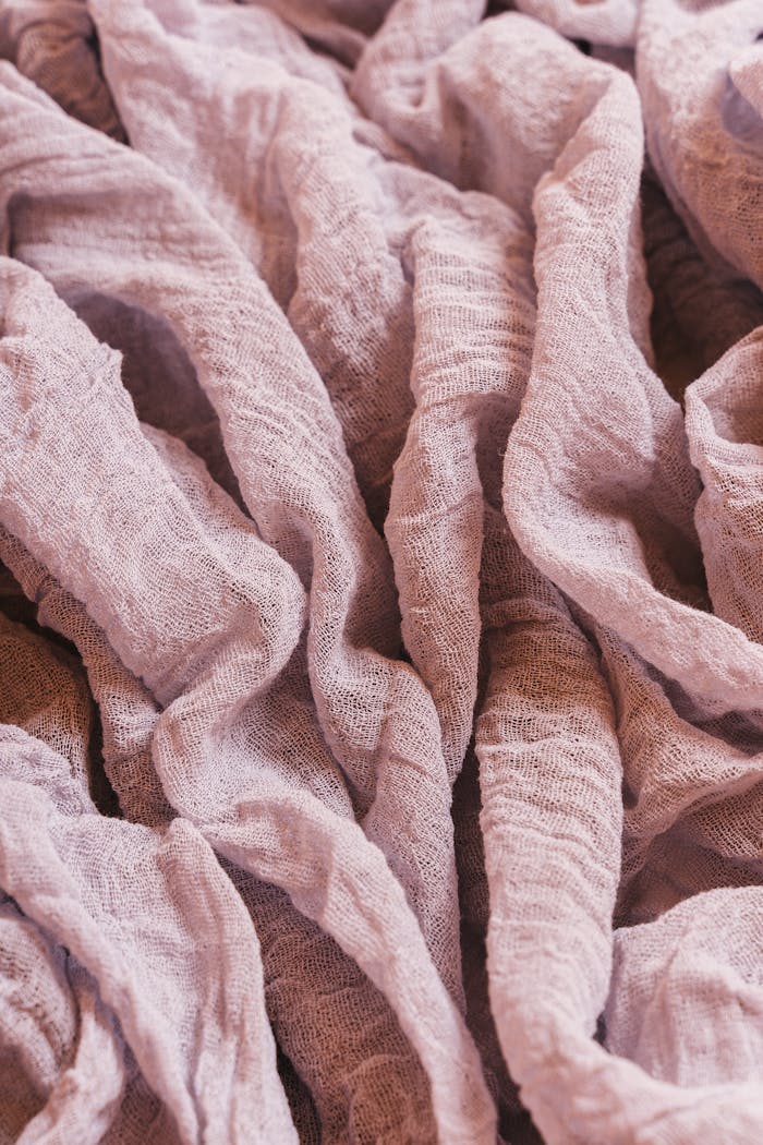 Close-up of crinkled purple linen fabric showcasing texture and folds. Ideal for design and textile concepts.
